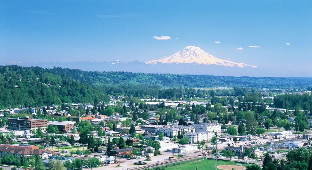 Sunset in Kent, Washington, with a mix of buildings, autumn trees, and Mount Rainier against a vibrant orange and yellow sky