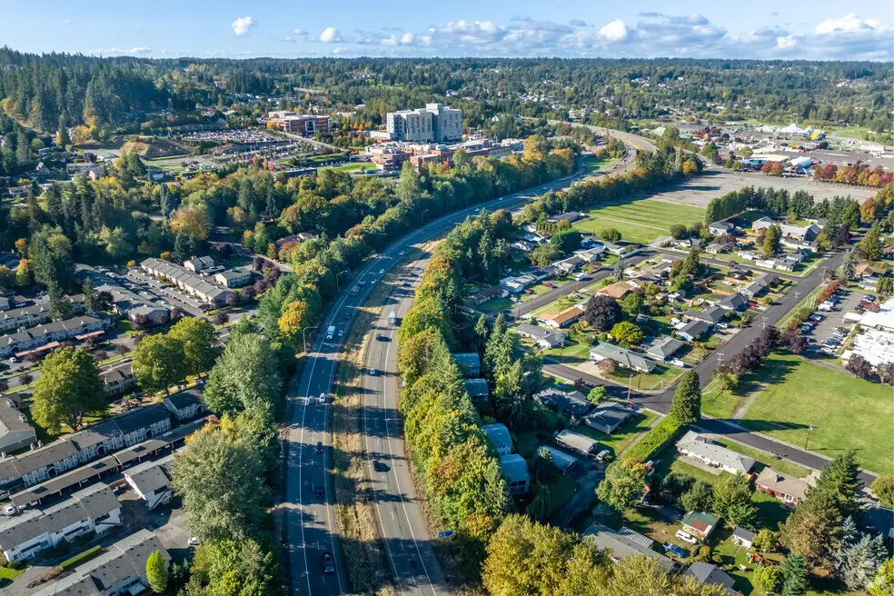 Aerial view of a highway through a suburban area with houses, trees, and a hospital.