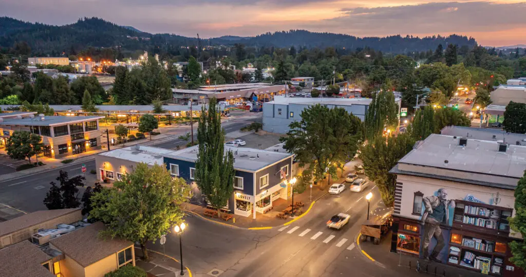 Downtown Springfield OR street corner at dusk, with warm lights from shops and cars. Local success is built on Website Design Springfield OR. (124 chars)