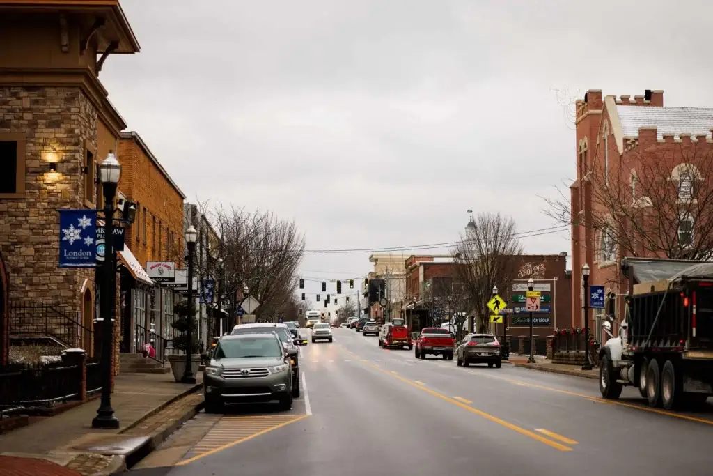 A wide street view of downtown London, KY, with traffic and cars parked along the curb under an overcast sky. For top-tier digital services, consider Website Design London KY.