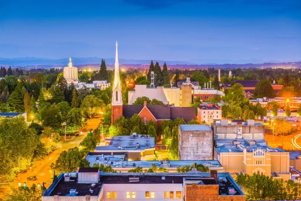 The Salem, OR, skyline at dusk, highlighting a church spire and the State Capitol dome, surrounded by trees and buildings. For superior digital services, consider Website Design Salem OR.