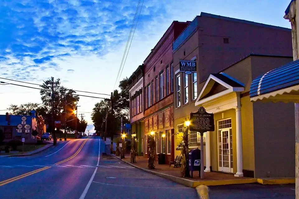A small town street at dusk with historic storefronts, a sloping road, and vibrant blue and orange sky, a great place for local Website Design Vine Grove KY.