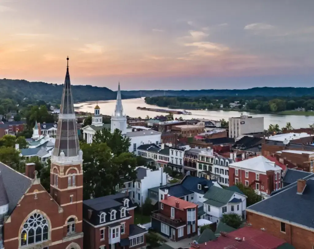 Elevated view of Maysville, KY downtown at dusk, featuring church spires, historic buildings, and the Ohio River flowing in the background, needing professional Website Design Maysville KY.