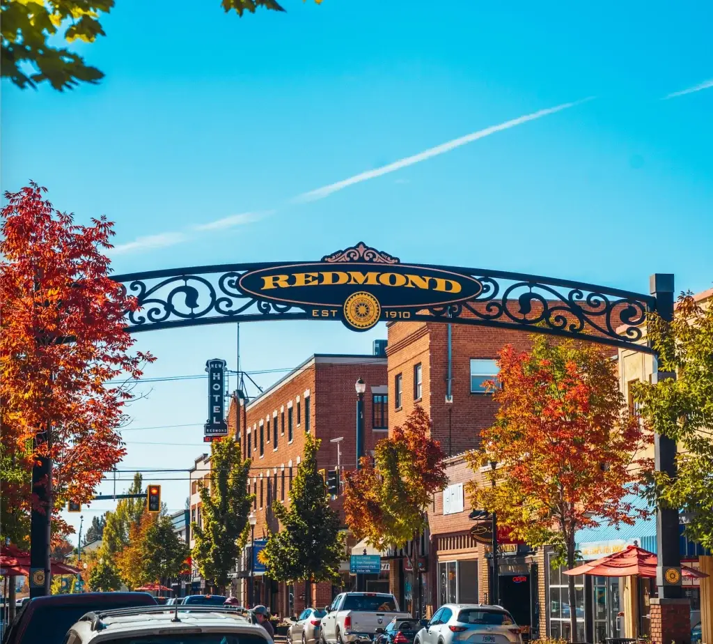 Downtown Redmond OR street scene under an iconic archway sign during the peak of autumn foliage. Community presence is strengthened by Website Design Redmond OR.