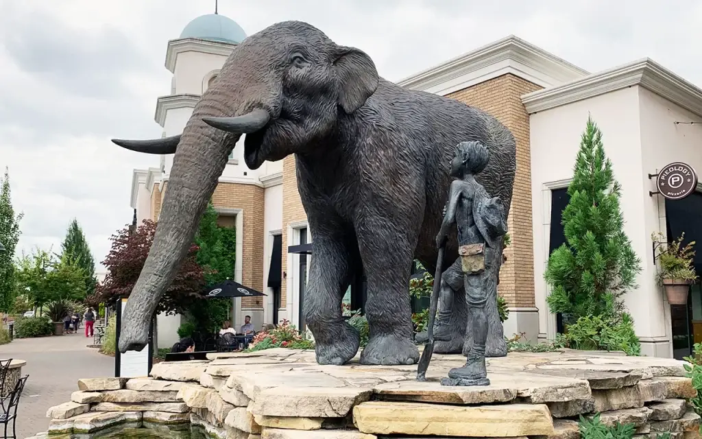Large bronze elephant and boy sculptures on a rock base at Bridgeport Village in Tualatin OR. Local attractions leverage Website Design Tualatin OR.